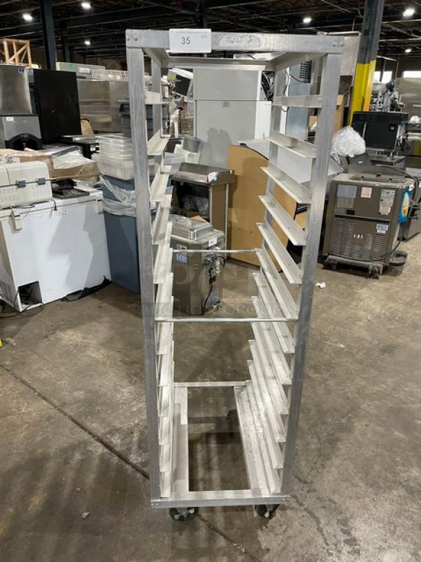 Metal bakery rack with multiple shelves, on wheels, in good condition, auction tag labeled "35" on top.