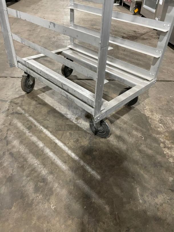 Industrial metal cart with four wheels, sturdy frame, slight wear. Ideal for transporting goods in warehouse settings.