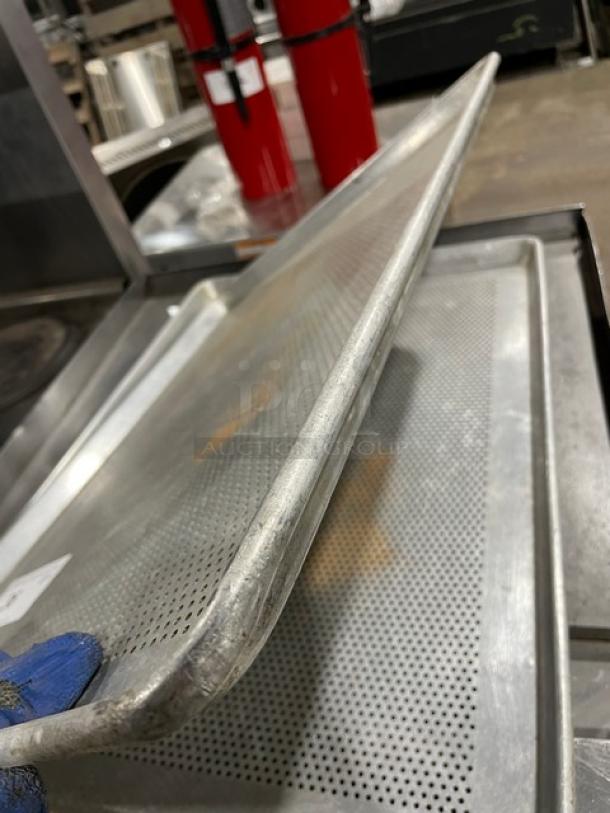 Perforated metal baking tray with raised edges, showing wear. Ideal for commercial kitchen use. No visible tags or markings.