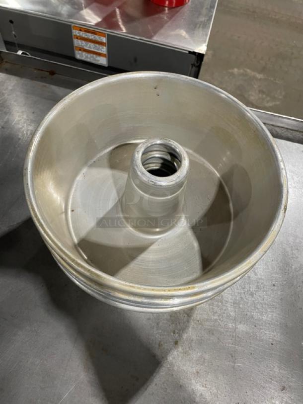 Metal bundt cake pan with tube center, shows wear, light scuffs, no visible markings, standard size.