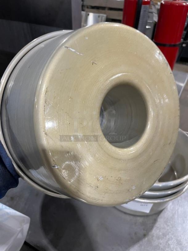 Ceramic wheel with central hole and visible wear, beige glaze, metallic rim, minor scuffs indicative of use.
