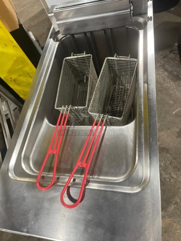 Commercial deep fryer with two metal baskets, red handles, in stainless steel. Appears in good condition.