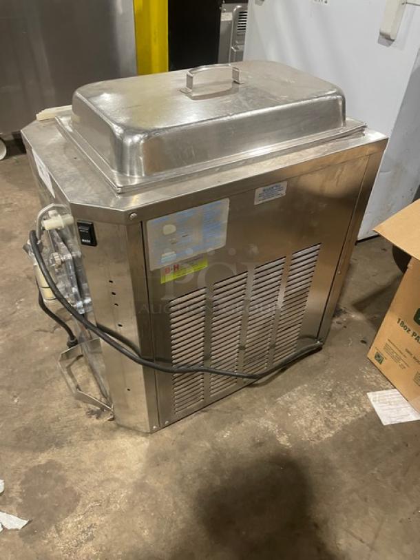 Commercial stainless steel freezer with lid, side vents, and visible power cord. Includes usage labels and signs of wear.