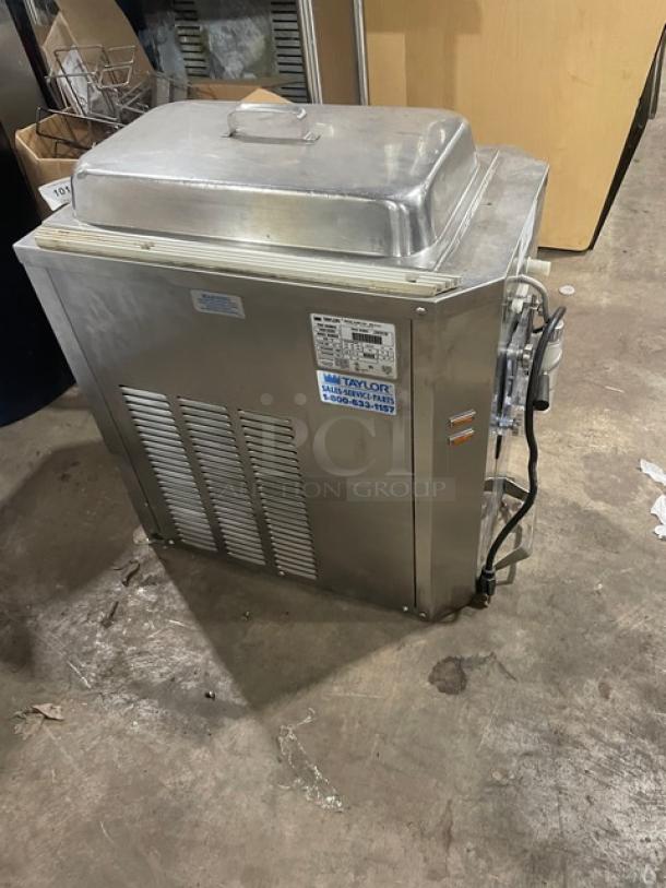 Commercial stainless steel Taylor soft serve machine. Features vented sides, labeled service sticker, power cord. Used condition.