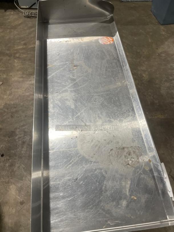 Stainless steel industrial tray, used condition with scratches and visible wear. Orange sticker on surface, unreadable.