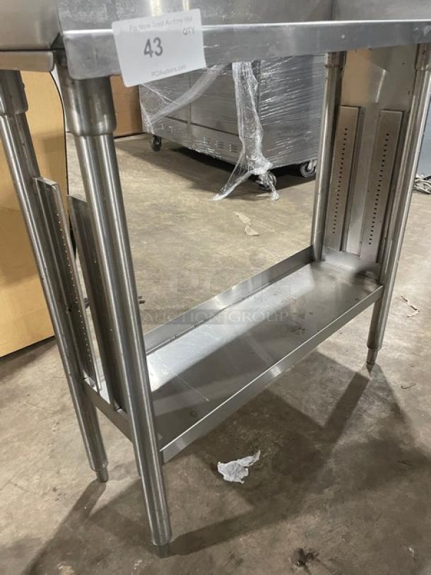 Stainless steel industrial table with lower shelf, open frame design, and durability, showing tag "43" for auction identification.