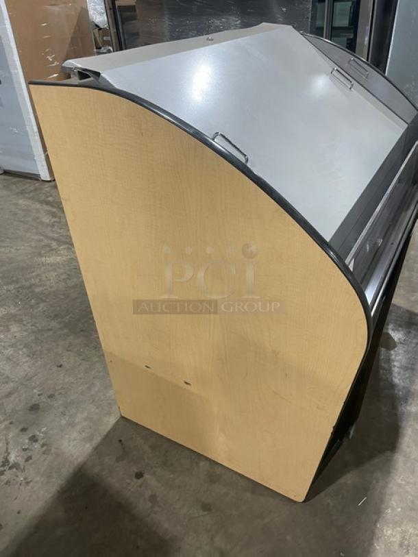 Wooden display case with curved sides, hinged glass front, and metal trim, in good condition, suitable for retail use.