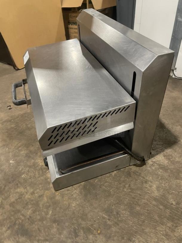 Stainless steel countertop grill, vented top, handles on sides, used condition, visible wear, tag with inventory number.