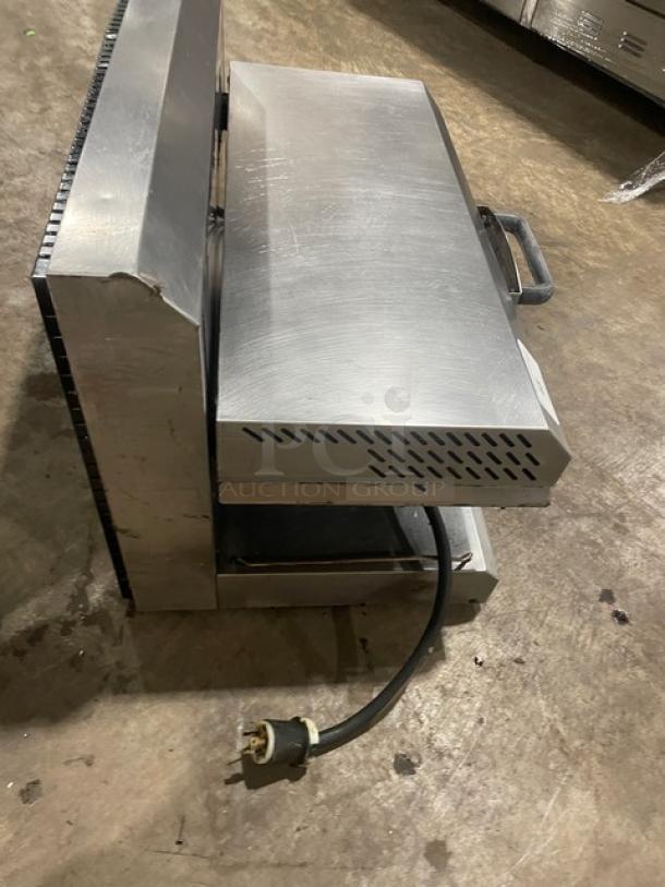 Commercial stainless steel sandwich press with handle and power cord, scuff marks visible, suitable for kitchen use.
