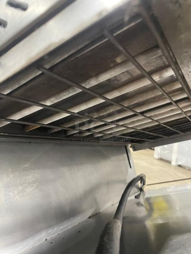 Commercial panini grill, stainless steel, with visible electric cord. Shows signs of use, grate in good condition.