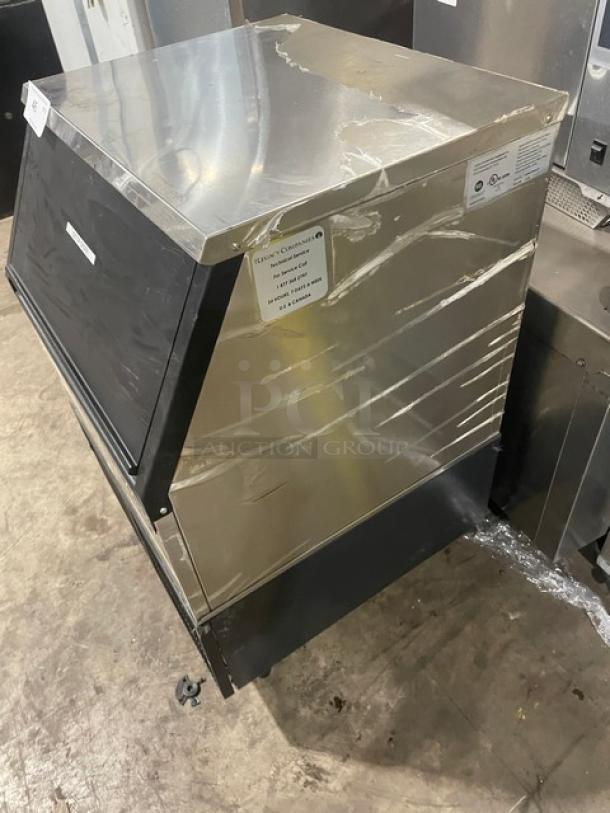 Commercial ice machine with stainless steel body, visibly good condition. Label states model and operational guidelines.
