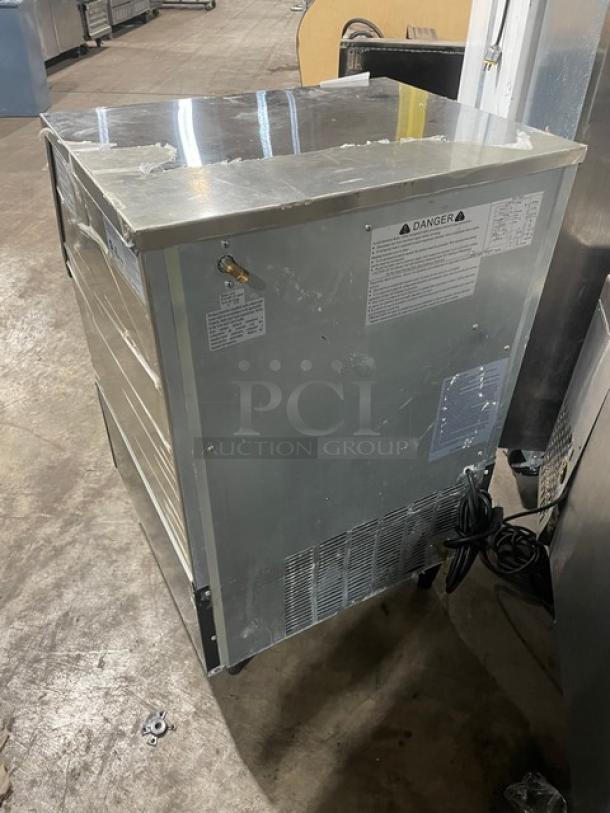 Commercial stainless steel ice maker, used condition, visible surface scratches. Warning labels and cord attached.