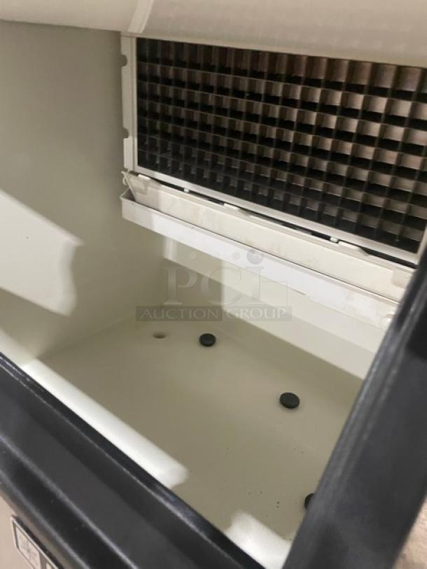 Commercial ice maker interior view, featuring clean white compartment and grid-like evaporator. Visible drainage holes, well-maintained.