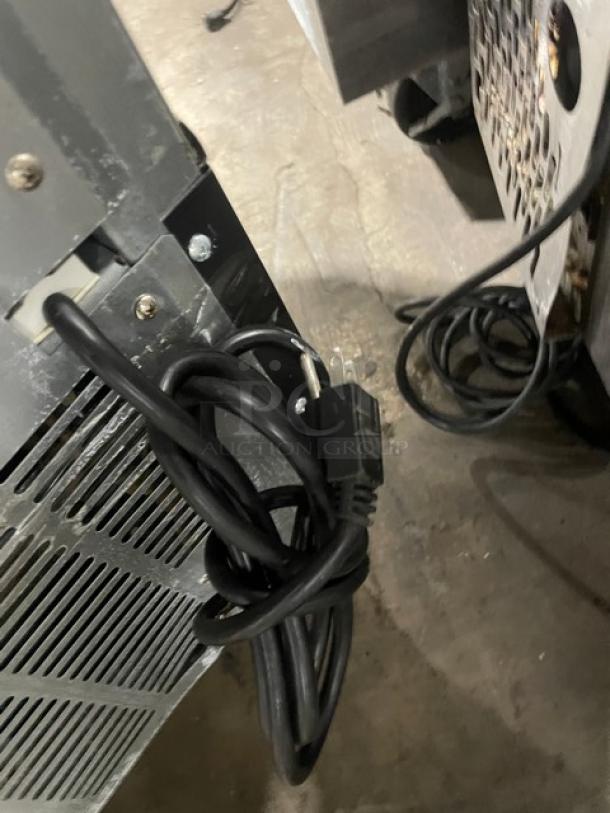 Industrial equipment with black power cord, metal casing shows signs of wear. Ventilation grille visible. Condition: used.