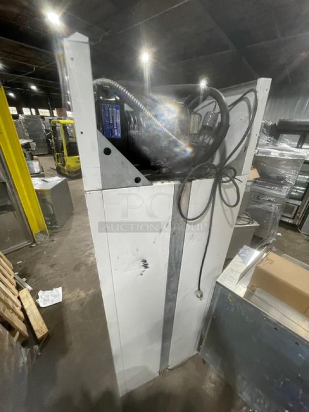 Industrial metal cabinet with visible scuffs, wires, and attached machinery, suggesting use in a workshop or factory.