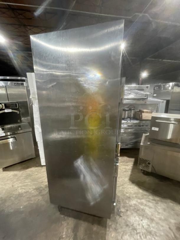 Stainless steel commercial refrigerator with two sturdy handles, minor surface scratches, in an industrial setting.