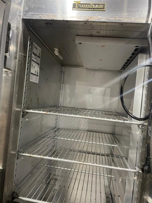 Commercial stainless steel warming cabinet with three wire shelves, interior light, and power cord. Slight wear visible.