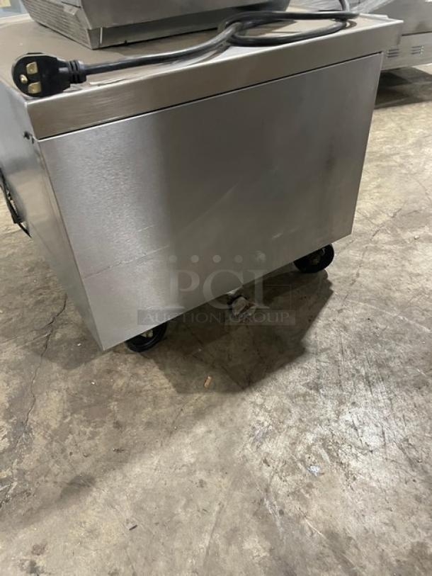 Stainless steel commercial kitchen appliance on wheels, featuring a power cord and plug. Appears in used condition.