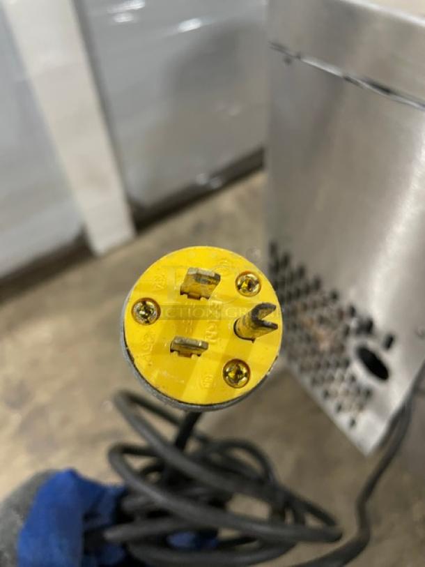 Close-up of a yellow electrical plug with three prongs and visible screws, attached to a black cord. Plug shows "Bryant" branding.