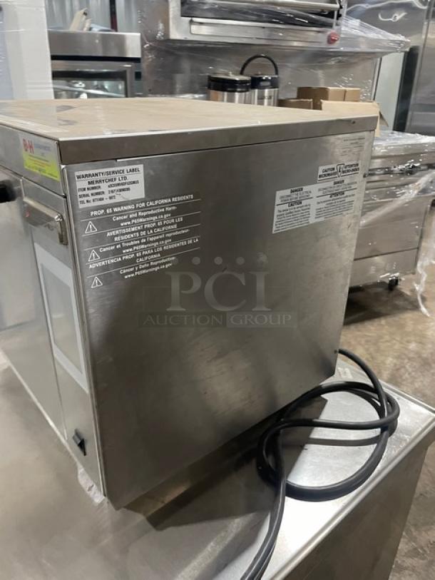 Commercial stainless steel appliance with visible power cord, warranty/service label, and safety warning for California residents.