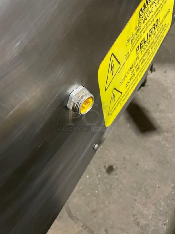 Metal panel with a yellow warning label and electrical socket. Label indicates high voltage. Appears in good condition.