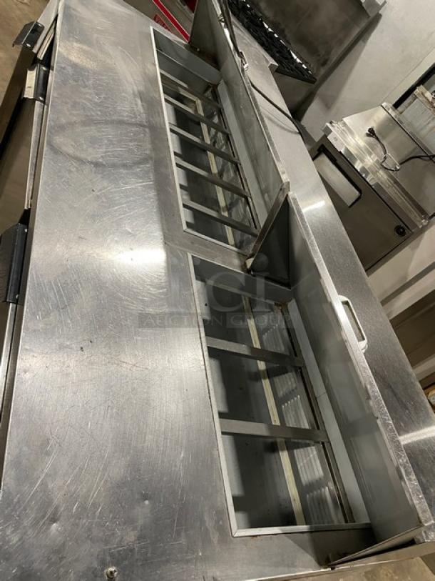 Stainless steel commercial refrigerator with open top sections and handle, showing signs of wear. Suitable for kitchen use.