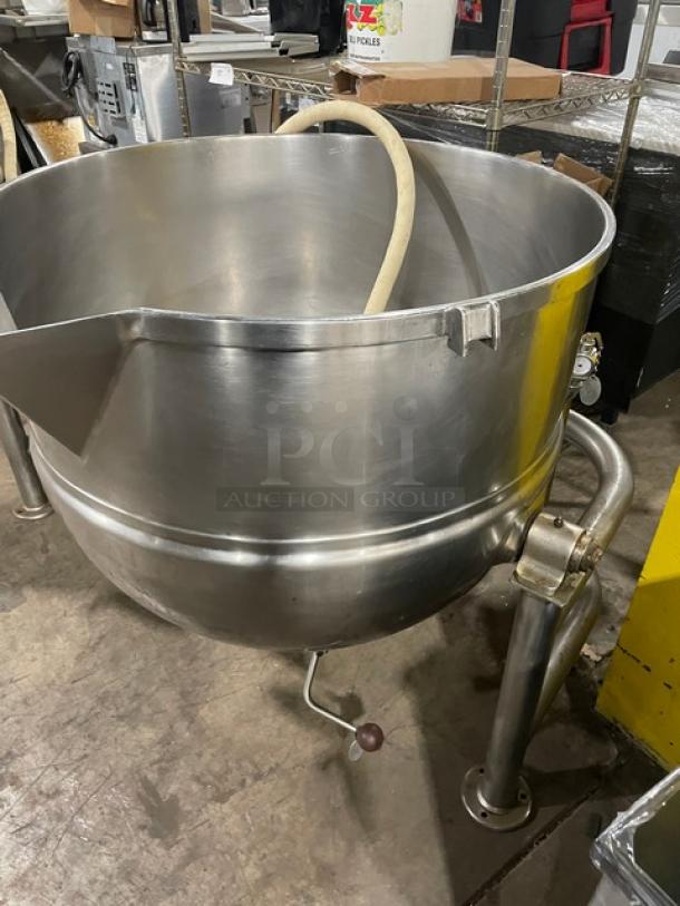Large stainless steel industrial mixing kettle with spout, manual tilt mechanism, and sturdy legs, in good condition.