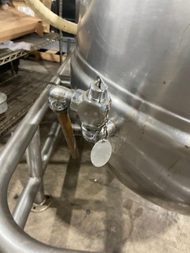 Stainless steel tank with spigot, industrial grade. Features a secure metal tag. Used condition with minor surface wear.