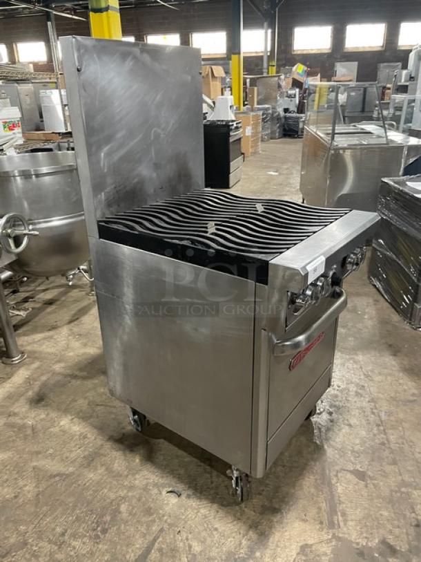 Commercial stainless steel charbroiler on wheels, featuring heavy-duty grilling surface, temperature knobs, and storage compartment. Used condition.