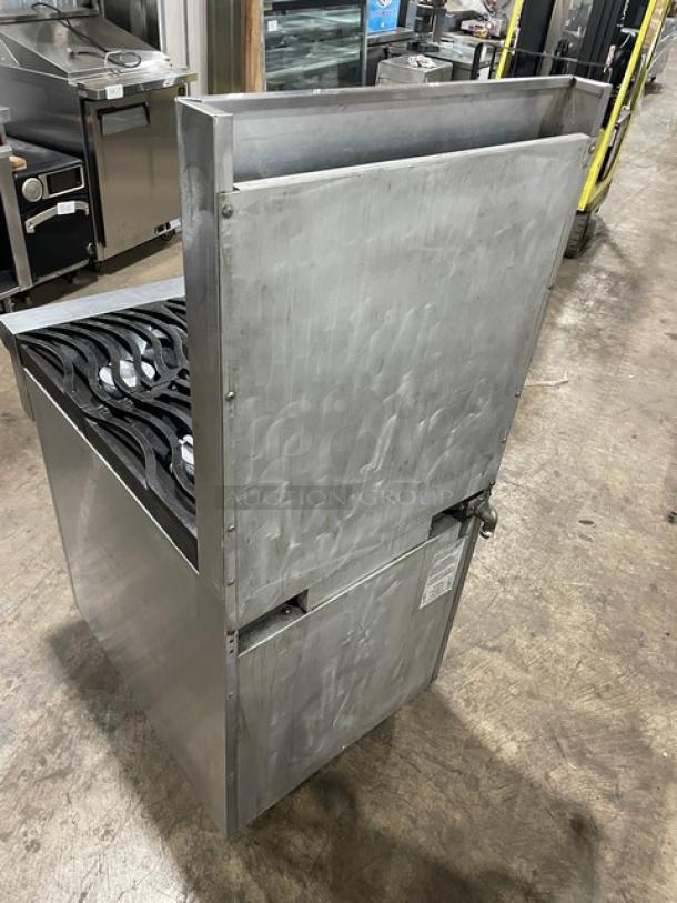 Stainless steel commercial stove with gas burners, showing moderate wear. Label indicates professional-grade usage.
