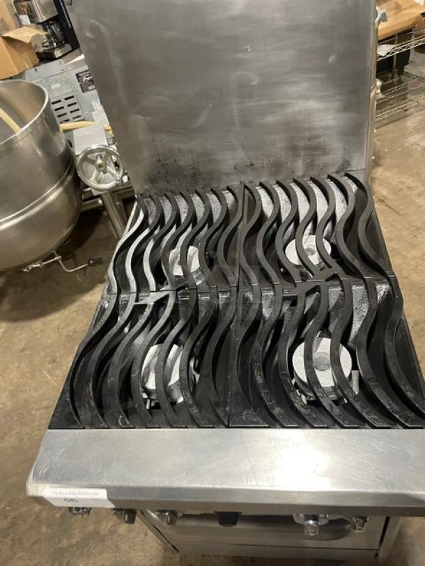 Commercial gas stove with six burners, wave-patterned grates, stainless steel body, and a clean surface. Ideal for professional kitchens.