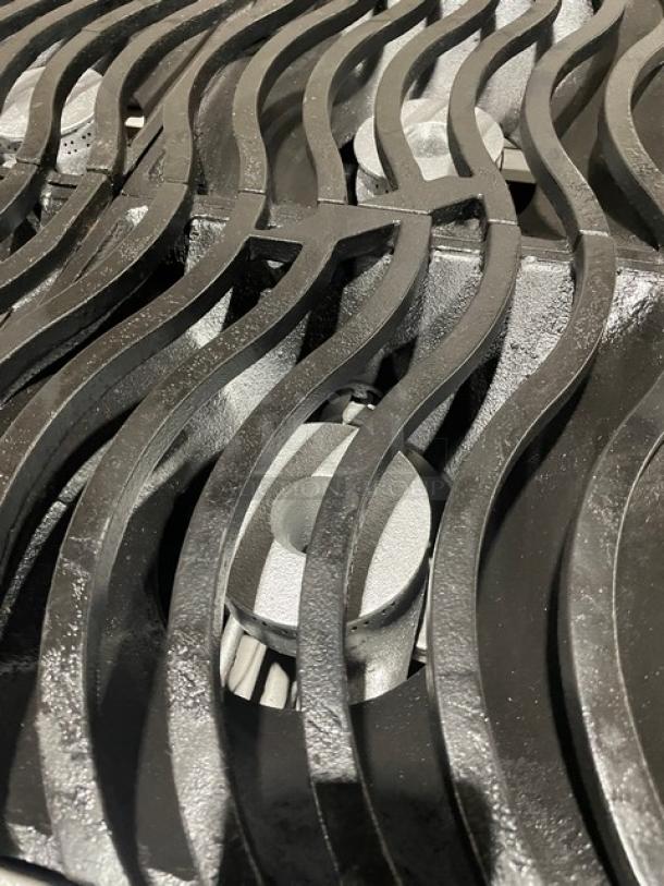 Black cast iron grill grate with wave design, in excellent condition, showing detailed craftsmanship and sturdy construction.