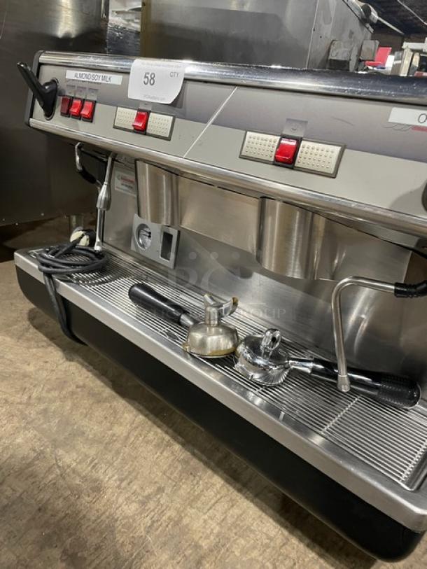Commercial espresso machine with dual portafilters, stainless steel finish, multiple control buttons, includes milk frother, tag "58".