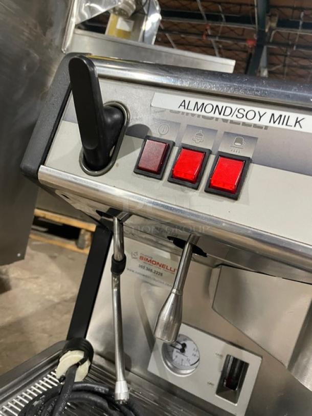 Commercial espresso machine marked "Almond/Soy Milk," with steam wand, three red buttons, Simonelli branding, good condition.