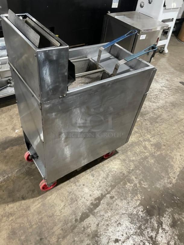 Stainless steel deep fryer on red wheels, dual baskets with blue handles, commercial use, good condition.