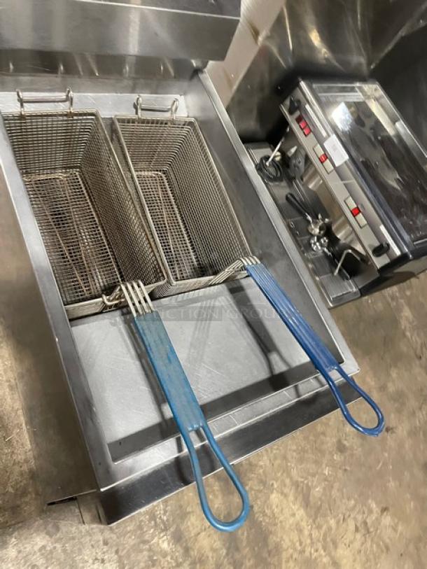 Commercial deep fryer with dual baskets and blue handles, stainless steel, well-maintained, includes a control panel.