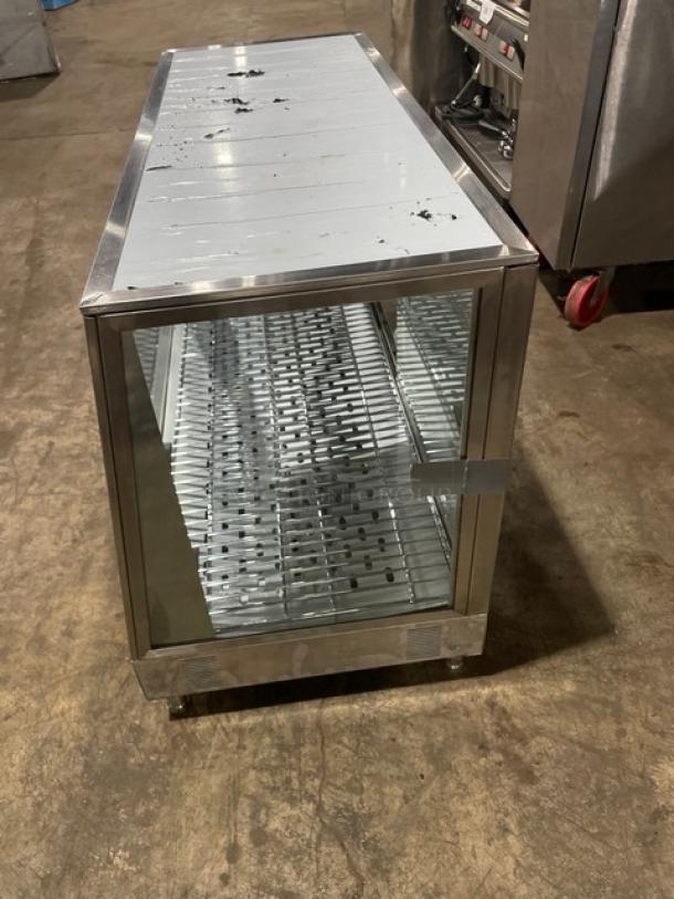 Stainless steel glass-front refrigerated display case with shelves, moderate wear, latch closure, on wheels.