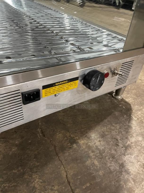 Stainless steel warming display case with adjustable temperature dial and power switch. Features a warning label.