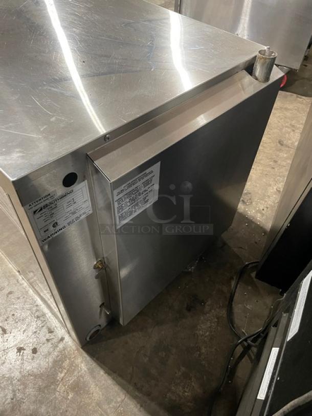 Stainless steel commercial refrigerator, upright design, with visible safety and operation labels; appears in good condition.