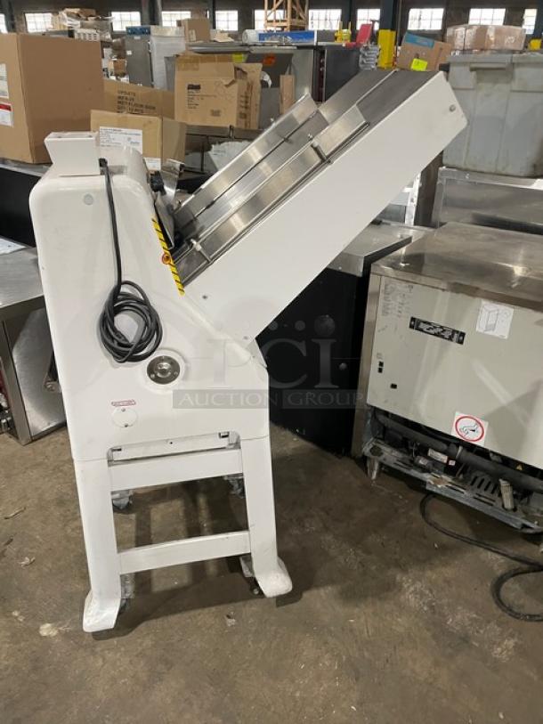 Industrial dough divider machine, white, stainless steel top, in used condition. Visible power cord, no discernible brand.