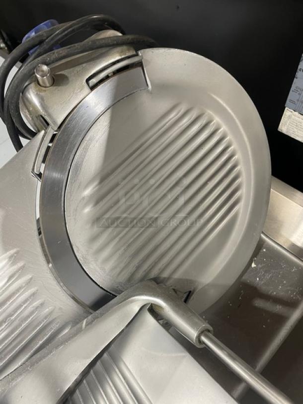 Industrial meat slicer in good condition, featuring a stainless steel blade and adjustable settings for slicing thickness.