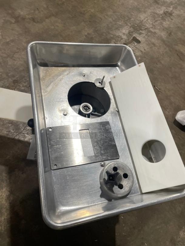 Industrial stainless steel grinder, tabletop model, visible blade housing, metal turn handle. Good condition, clean surface.