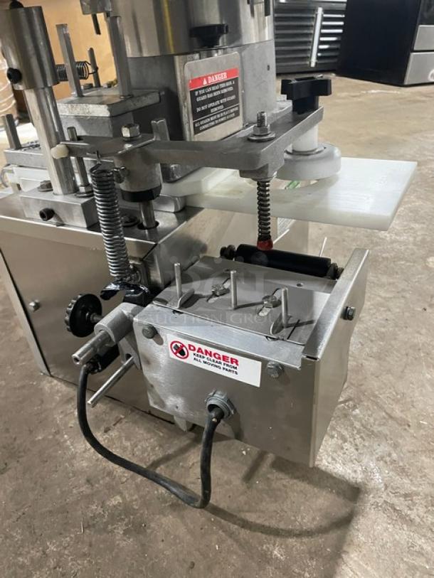 Industrial automated labeling machine in used condition, featuring metal construction and visible safety warning labels.