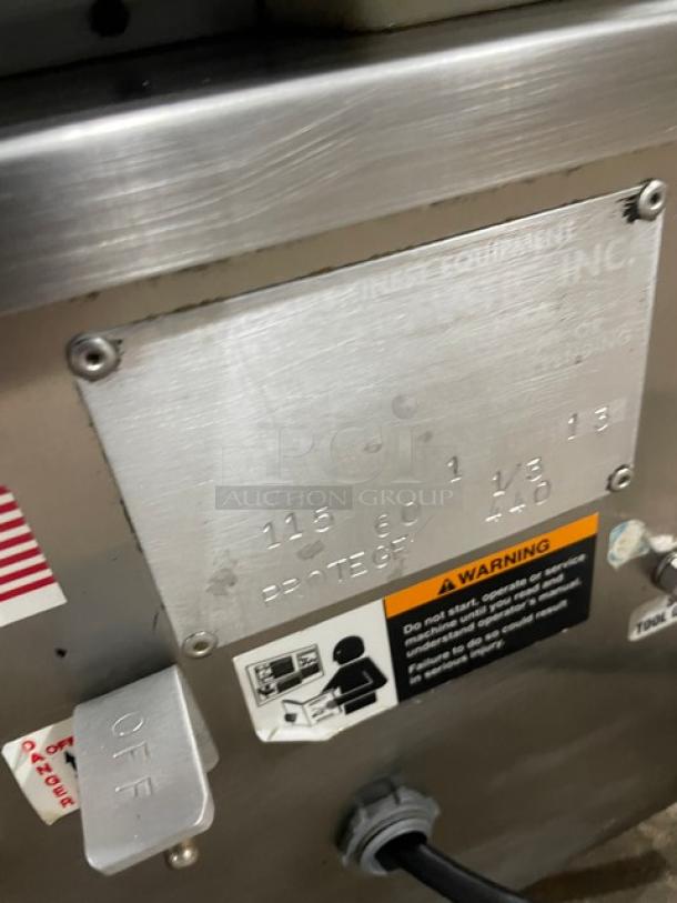 Industrial machine panel with metal identification plate displaying specifications like voltage and frequency. Includes safety warning labels.