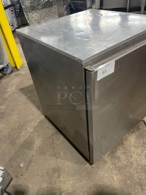 Stainless steel commercial refrigerator, single door, industrial-grade, label shows "65," minor surface wear visible.