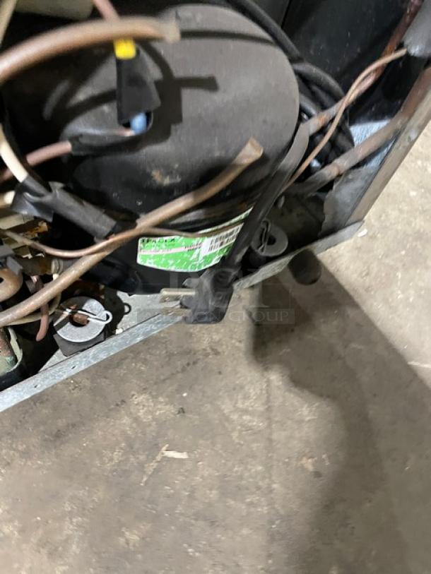 HVAC compressor unit with electrical wiring, metallic components, and a visible green maintenance label. Good condition.