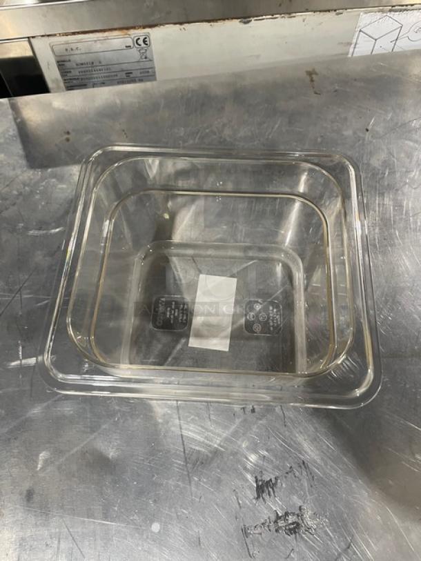 Clear rectangular glass baking dish on metal surface, visible label with care symbols inside.