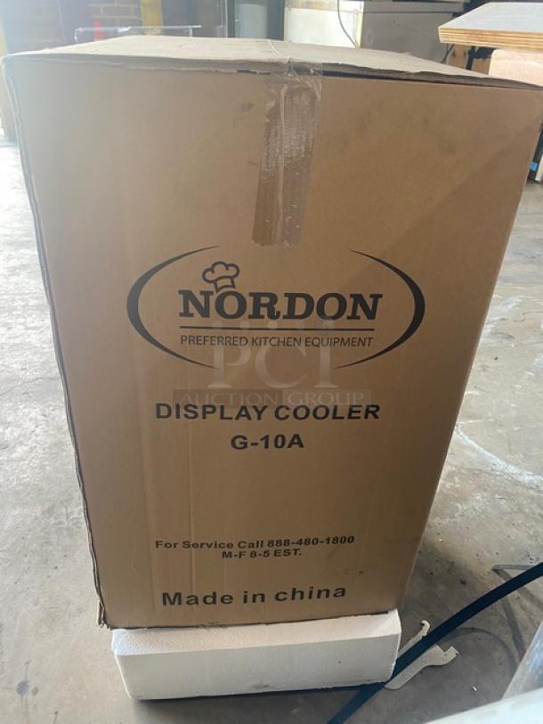 Nordon G10A countertop merchandiser display cooler in box. Features black single glass door, poly coated wire racks, lock, and keys.