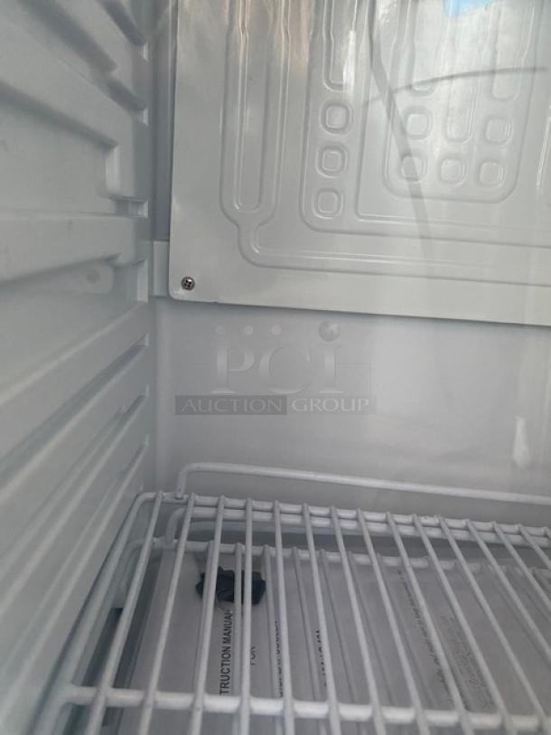 Nordon G10A display cooler interior with poly-coated wire racks, white walls, and instruction manual visible.