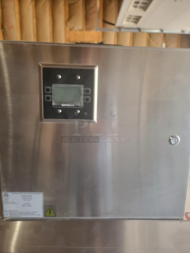 Stainless steel industrial control panel with digital display and safety label, model details partially visible.